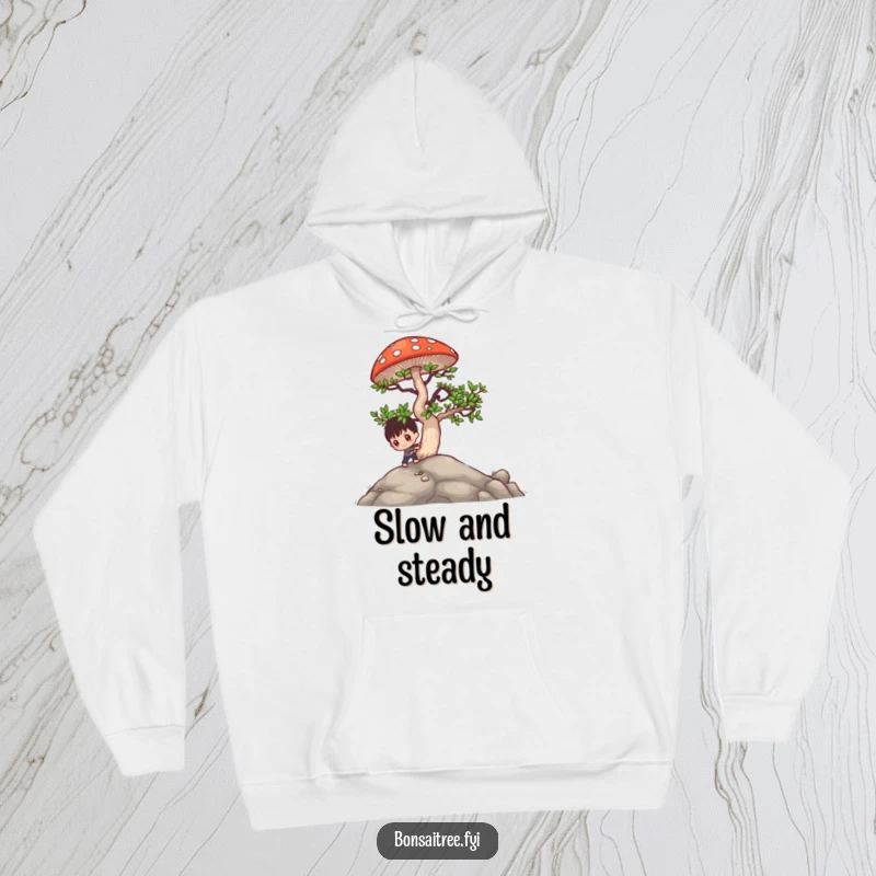Funny bonsai character pushing a large mushroom uphill, depicted on a cozy hoodie, symbolizing perseverance with a humorous spirit.